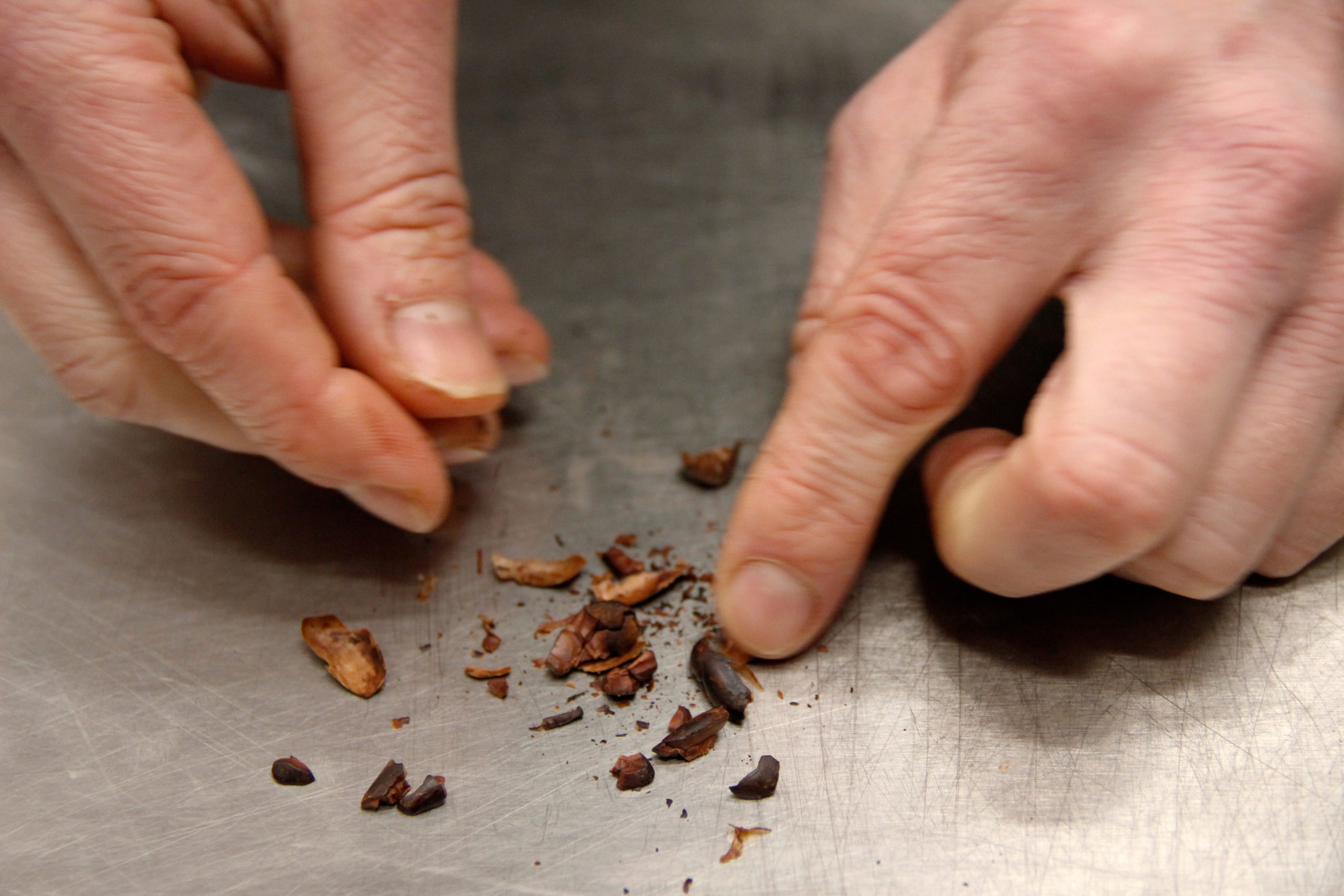 Bild på Johans händer som separera skalet på kakaobönan från kakaonibsen